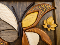 Close-up craftsmanship detail showing carved leaves, flower forms and carefully shaped relief intarsia elements.